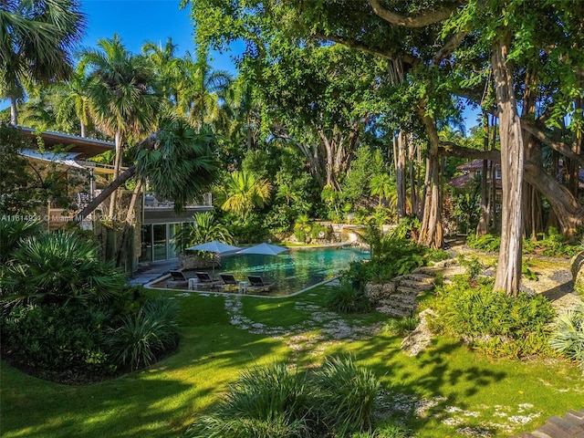 view of property's community featuring a lawn and a patio area