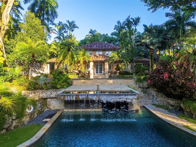 back of property featuring a water view, a patio, and pool water feature