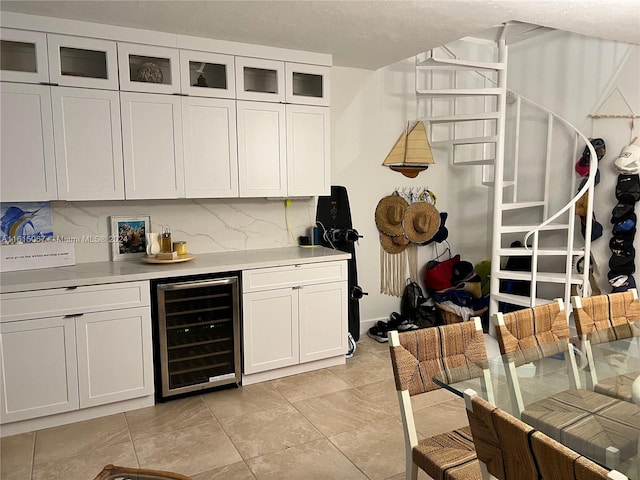 kitchen featuring white cabinets, light tile patterned floors, backsplash, and beverage cooler