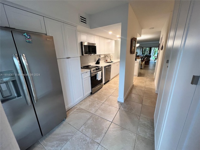 kitchen featuring white cabinetry, sink, light tile patterned flooring, and appliances with stainless steel finishes