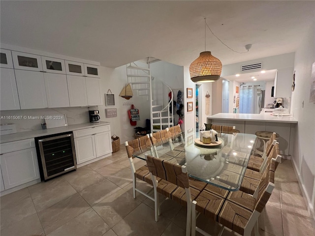 kitchen with backsplash, wine cooler, decorative light fixtures, white cabinetry, and light tile patterned flooring