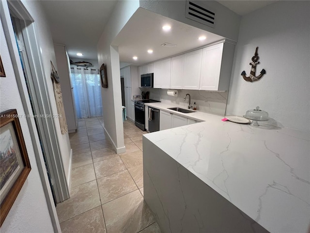 kitchen featuring sink, stainless steel appliances, light tile patterned floors, light stone counters, and white cabinets