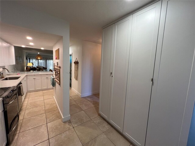 kitchen featuring white cabinetry, sink, light tile patterned floors, and stainless steel appliances