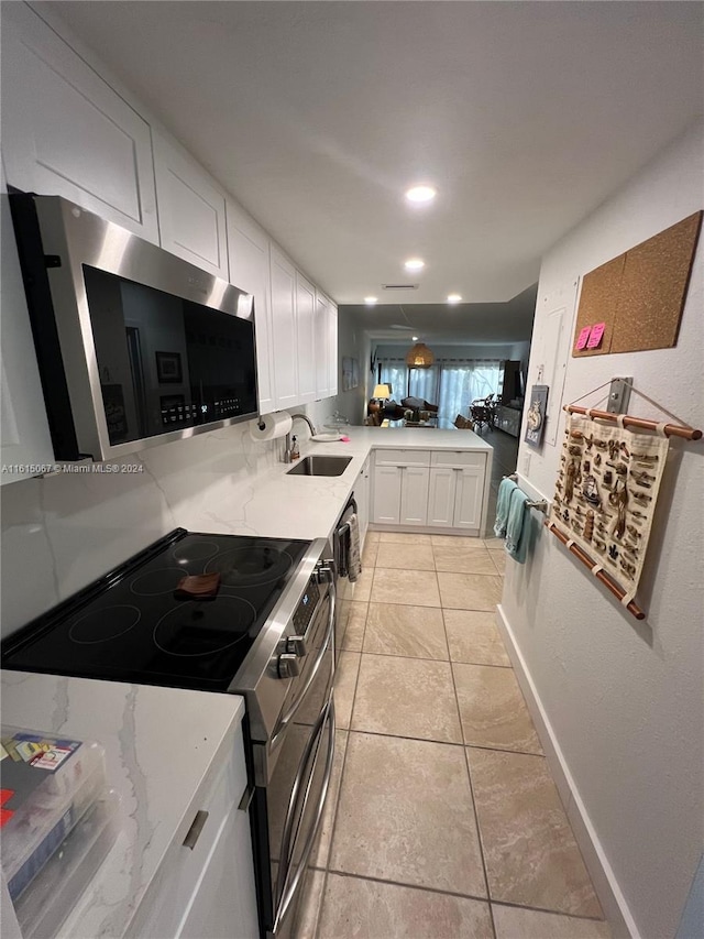 kitchen featuring light tile patterned flooring, light stone countertops, white cabinetry, and kitchen peninsula