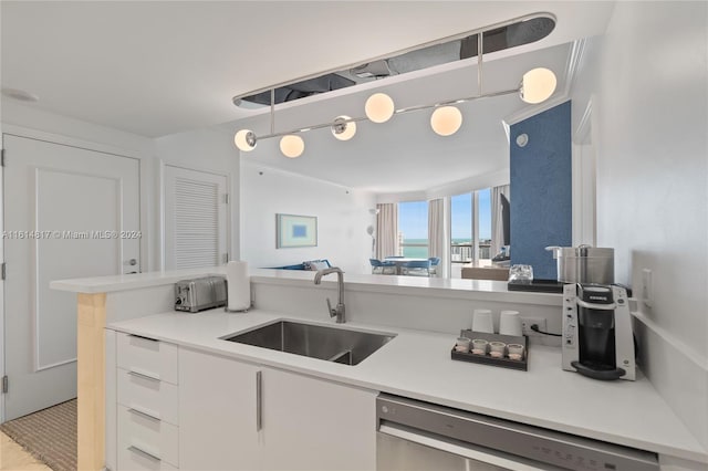 kitchen with white cabinets, sink, kitchen peninsula, stainless steel dishwasher, and decorative light fixtures