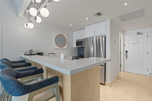 kitchen with kitchen peninsula, white cabinetry, stainless steel appliances, a kitchen breakfast bar, and a notable chandelier