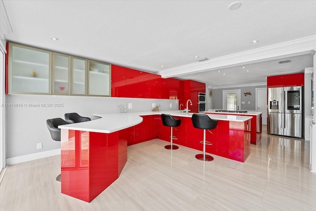 kitchen with kitchen peninsula, a breakfast bar area, stainless steel appliances, sink, and a center island