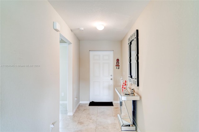 hall featuring light tile patterned floors and a textured ceiling