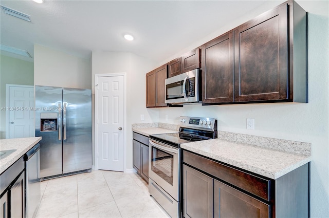 kitchen featuring light stone counters, dark brown cabinets, light tile patterned flooring, and appliances with stainless steel finishes