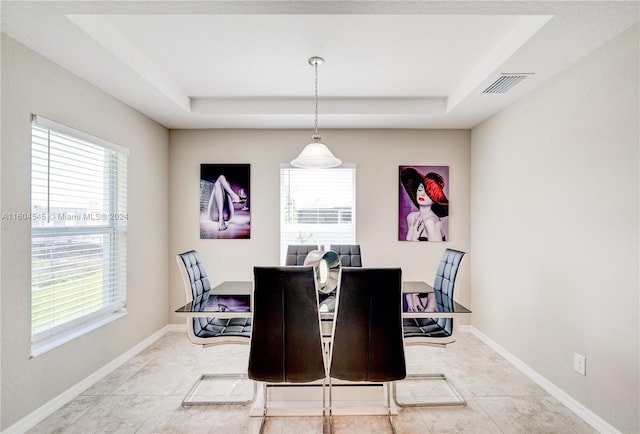 tiled dining room featuring a tray ceiling