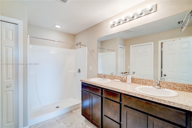 bathroom with a shower, vanity, and tile patterned floors