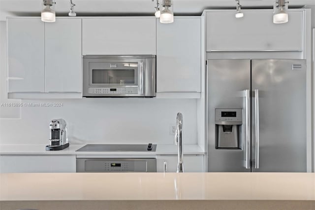 kitchen with black electric cooktop, sink, pendant lighting, stainless steel fridge with ice dispenser, and white cabinetry