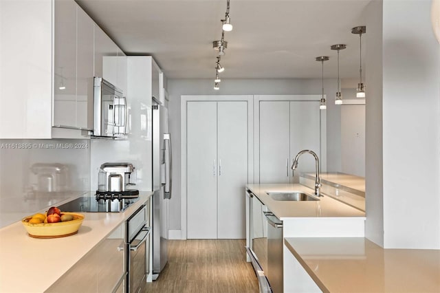 kitchen featuring decorative backsplash, appliances with stainless steel finishes, sink, white cabinets, and hanging light fixtures