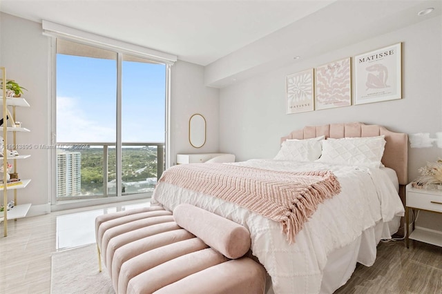 bedroom with multiple windows, light wood-type flooring, and floor to ceiling windows