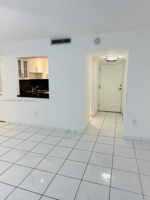 unfurnished room featuring light tile patterned floors, a textured ceiling, and sink