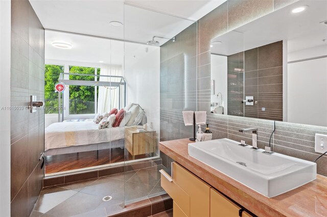 bathroom with tile floors, vanity, and tile walls