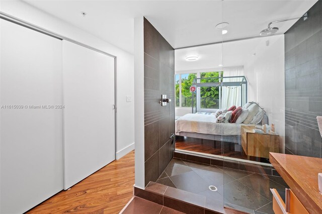 bedroom with a closet, light wood-type flooring, and tile walls