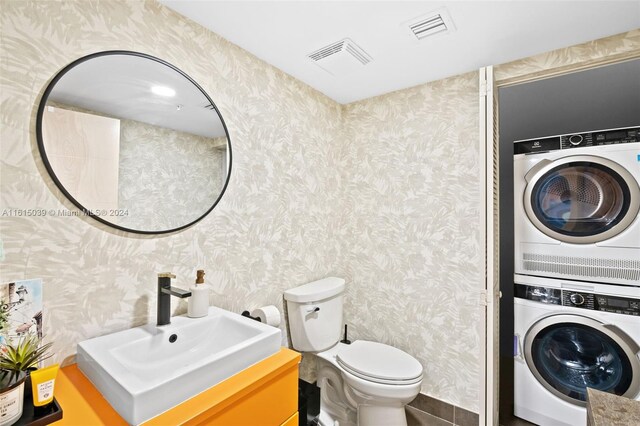 bathroom featuring stacked washer / dryer, vanity, and toilet