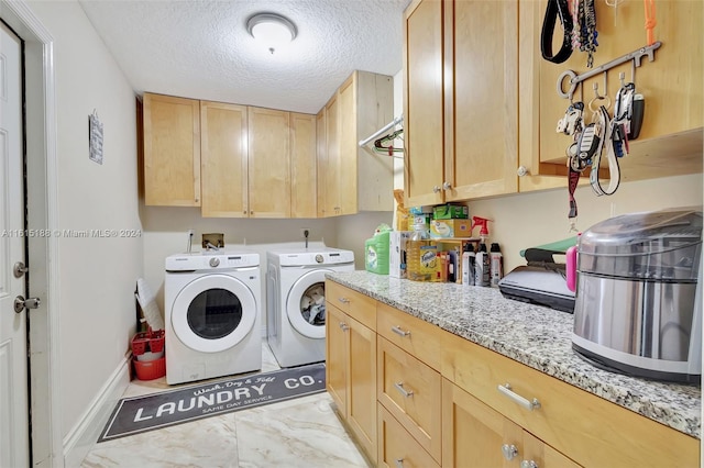 clothes washing area featuring cabinets, washer and dryer, and a textured ceiling