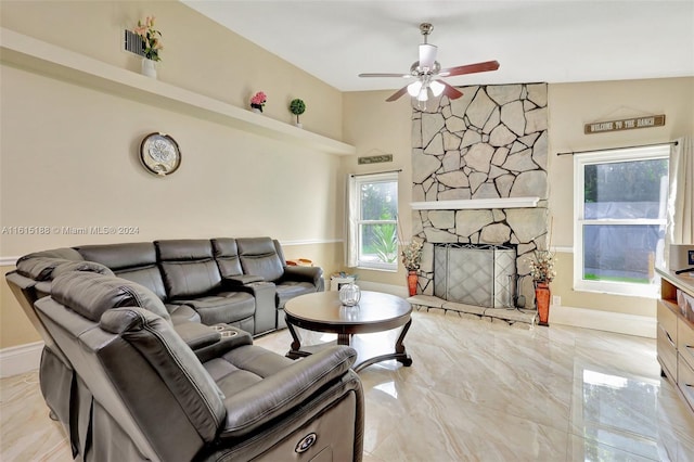 living room featuring high vaulted ceiling, ceiling fan, and a stone fireplace