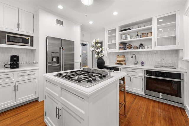 kitchen with a kitchen breakfast bar, decorative backsplash, white cabinetry, and stainless steel appliances