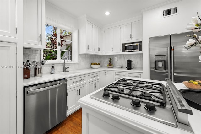 kitchen with white cabinets, sink, decorative backsplash, appliances with stainless steel finishes, and dark hardwood / wood-style flooring