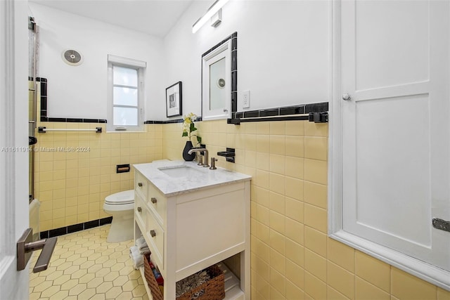 bathroom featuring tile patterned floors, vanity, tile walls, and toilet