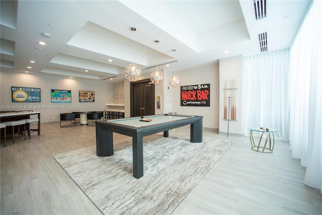 game room featuring a tray ceiling, pool table, and light wood-type flooring