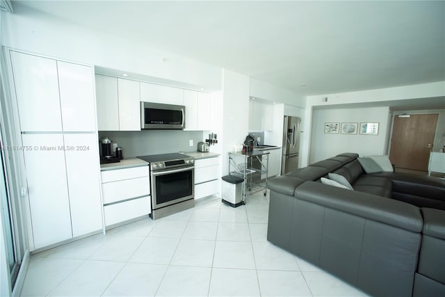 kitchen featuring light tile patterned floors, appliances with stainless steel finishes, and white cabinetry