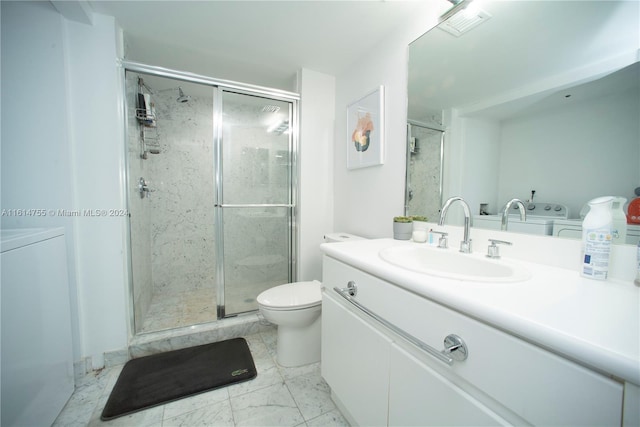 bathroom featuring toilet, independent washer and dryer, vanity, and a shower with shower door