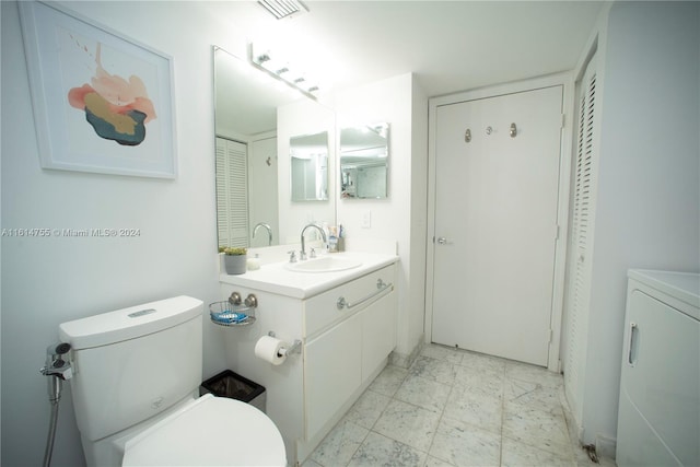 bathroom featuring toilet, washer / clothes dryer, and vanity