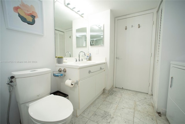 bathroom featuring toilet, washer / clothes dryer, and vanity