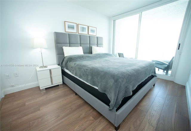 bedroom with floor to ceiling windows and hardwood / wood-style flooring