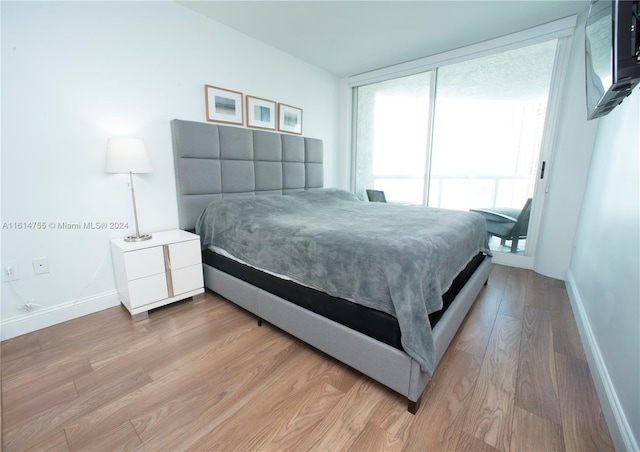 bedroom with expansive windows and light hardwood / wood-style flooring