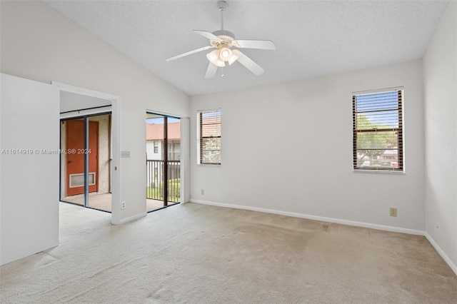 carpeted spare room featuring ceiling fan, lofted ceiling, a wealth of natural light, and a barn door