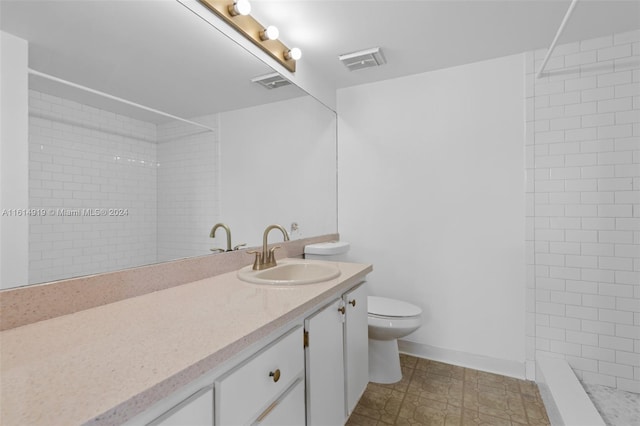 bathroom featuring vanity, a tile shower, and toilet