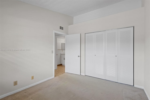 unfurnished bedroom with a closet and light carpet