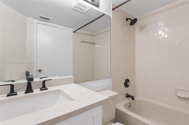 full bathroom featuring tiled shower / bath, vanity, and toilet