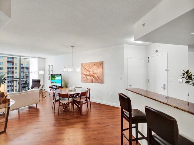 dining room featuring floor to ceiling windows, a textured ceiling, hardwood / wood-style flooring, and a chandelier