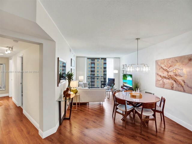 dining room featuring a textured ceiling, wood-type flooring, and an inviting chandelier