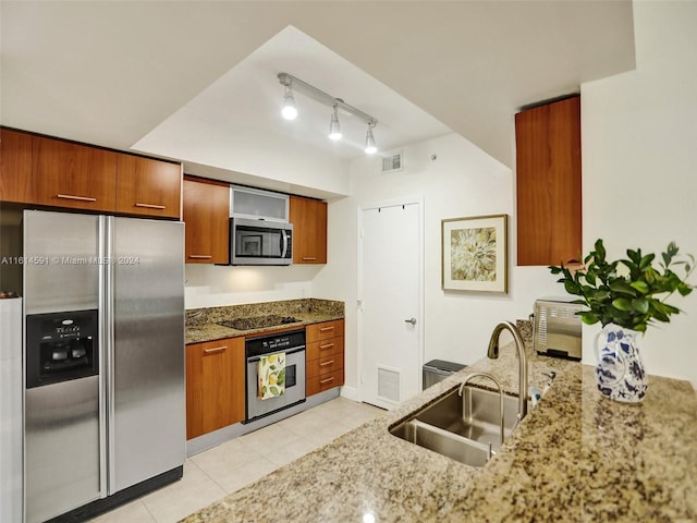 kitchen featuring sink, light tile patterned floors, stone counters, stainless steel appliances, and track lighting