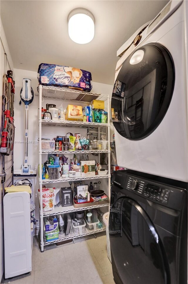 laundry room featuring tile floors and stacked washer and dryer