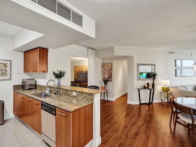 kitchen featuring sink, light stone countertops, stainless steel dishwasher, kitchen peninsula, and light wood-type flooring