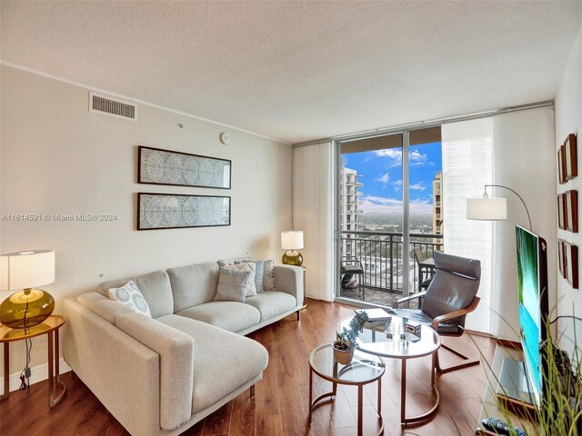 living room featuring a textured ceiling, a wall of windows, and wood-type flooring