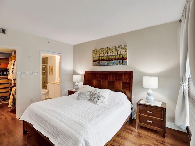 bedroom featuring ensuite bath, a walk in closet, a closet, and wood-type flooring