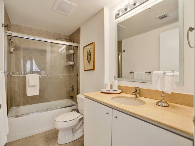 full bathroom featuring combined bath / shower with glass door, toilet, tile floors, and large vanity