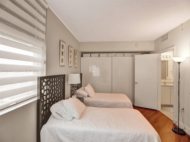 bedroom featuring ensuite bath and dark tile floors