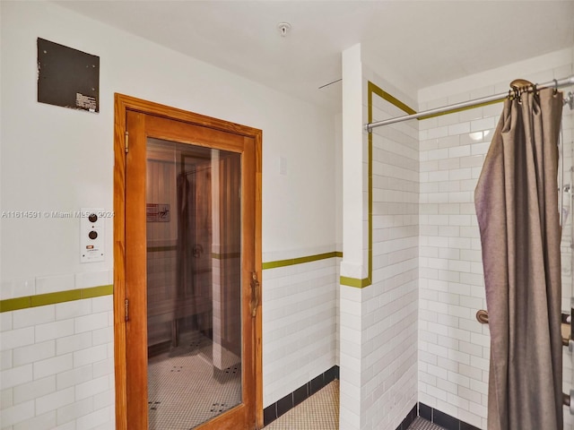 bathroom featuring curtained shower and tile walls