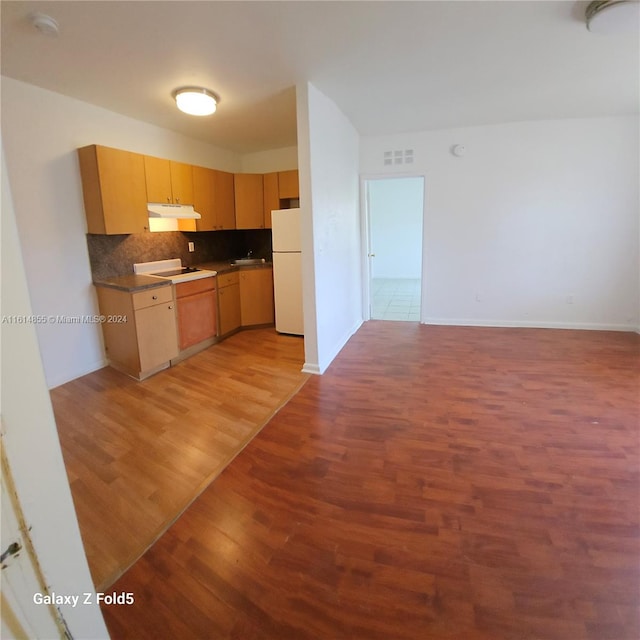 kitchen with backsplash, light brown cabinetry, light wood-type flooring, sink, and white refrigerator