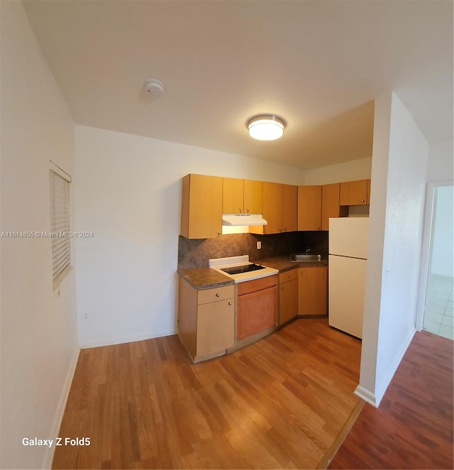 kitchen with white appliances, tasteful backsplash, sink, and light wood-type flooring